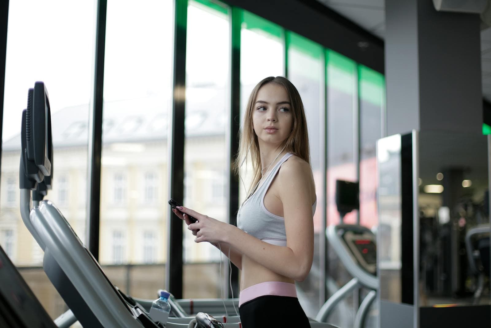 Adhérente dans une salle de sport utilisant l’app sur son smartphone